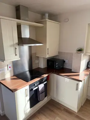 a kitchen with white cabinets and a stove top oven at Sea Spire Coach House in Charlestown