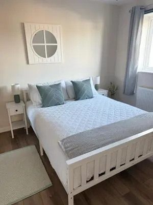 a white bed in a bedroom with two night stands at Sea Spire Coach House in Charlestown