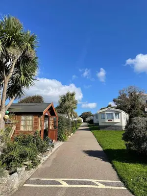 a walkway leading to a house with palm trees at Mounts Bay Caravan Park in Penzance