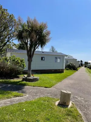 a house with a tree on the side of a road at Mounts Bay Caravan Park in Penzance