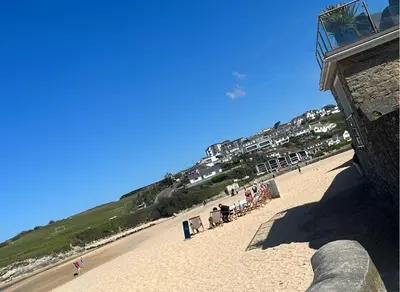 a beach with a group of people sitting on the sand at Peaceful room near to beach - Newquay Porth in Saint Columb Minor