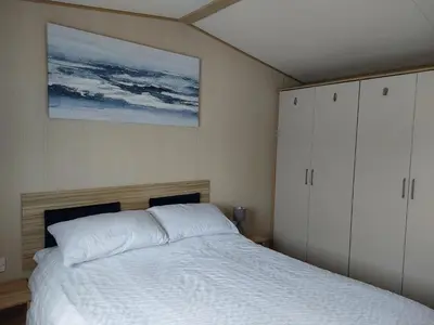 a bedroom with a bed and a painting on the wall at Gateway to Cornwall in St Austell