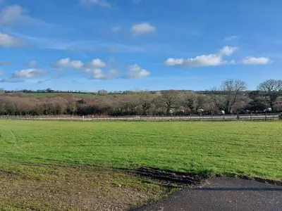 a large green field with a fence and trees at Gateway to Cornwall in St Austell