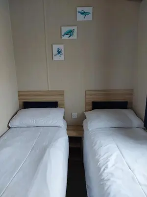 two beds in a room with three pictures on the wall at Gateway to Cornwall in St Austell