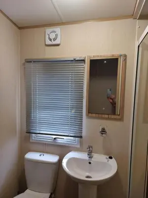a bathroom with a toilet and a sink and a window at Gateway to Cornwall in St Austell