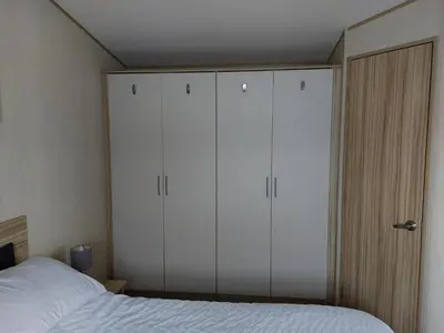 a bedroom with white cabinets and a bed at Gateway to Cornwall in St Austell