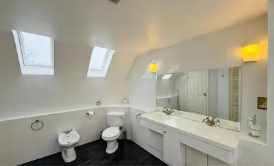 a white bathroom with two sinks and a toilet at Hustyn Lodges in Saint Wenn