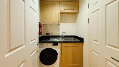 a small kitchen with a sink and a washing machine at Hustyn Lodges in Saint Wenn