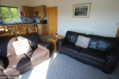 a living room with two leather couches and a kitchen at TwoPigalliie Heights in Nancekuke