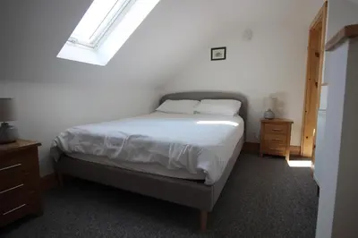 a bedroom with a bed with white sheets and a window at TwoPigalliie Heights in Nancekuke