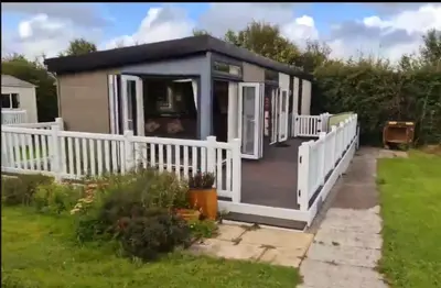 a tiny house with a porch and a white fence at Swift in Saint Columb Road Station
