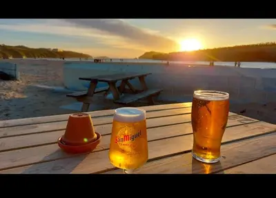 two glasses of beer sitting on top of a wooden table at Newquay Seaside Lodge Retreat with Hot Tub in Newquay