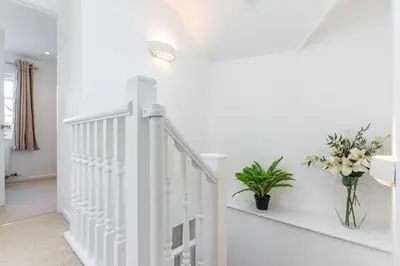a white staircase in a home with a vase of flowers at The White House in Wadebridge