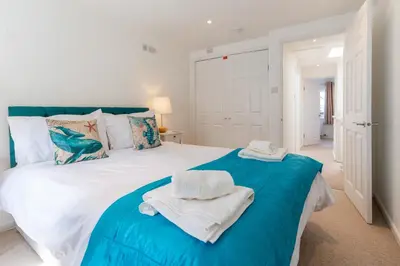 a bedroom with a blue and white bed with towels on it at The White House in Wadebridge