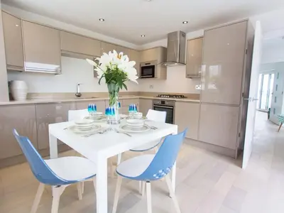 a kitchen with a white table and blue chairs at 7 Atlantic Watch in St Ives