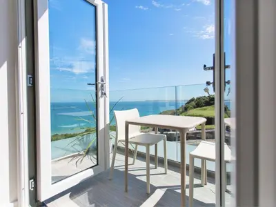 a table and chairs on a balcony with a view of the ocean at 7 Atlantic Watch in St Ives