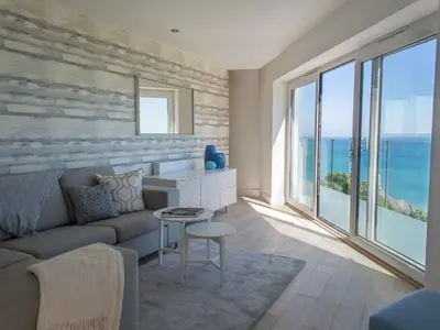 a living room with a couch and large windows at 7 Atlantic Watch in St Ives