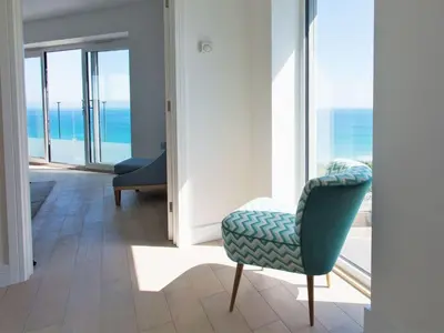 a room with a chair and a view of the ocean at 7 Atlantic Watch in St Ives