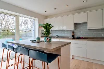 a kitchen with white cabinets and a table with chairs at Finest Retreats - Tamsin in Newquay