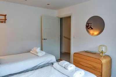 a bedroom with two beds and a mirror on the wall at Finest Retreats - Tamsin in Newquay