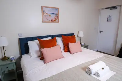 a bed with pink and orange pillows on it at Epiphany House in Kenwyn