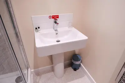 a white sink in a bathroom next to a shower at Epiphany House in Kenwyn