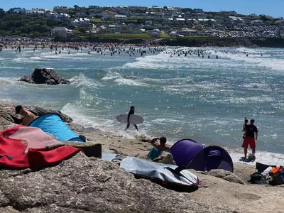a group of people on the beach with people in the water at Rocksalt in Saint Minver