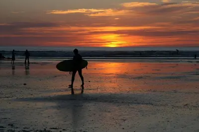 a person walking on the beach with a surfboard at Rocksalt in Saint Minver