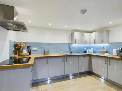 a kitchen with white cabinets and wooden counter tops at Sun Trap Terrace in Porthleven