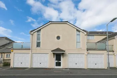 a house with white garage doors on a street at Coastal Breeze in Carbis Bay