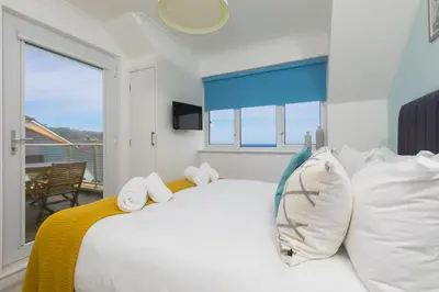 a bedroom with a large white bed with a window at Coastal Breeze in Carbis Bay
