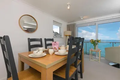 a dining room with a table and chairs and a mirror at Coastal Breeze in Carbis Bay