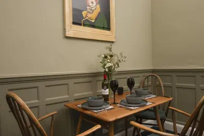 a wooden table with chairs and a painting on the wall at The Secret Seascape - Free Parking - Free WiFi - Carbis Bay in Carbis Bay