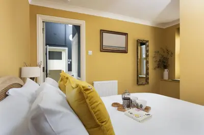 a bedroom with a white bed with yellow walls at The Secret Seascape - Free Parking - Free WiFi - Carbis Bay in Carbis Bay