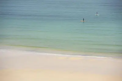 two people in the ocean with surfboards in the water at The Secret Seascape - Free Parking - Free WiFi - Carbis Bay in Carbis Bay