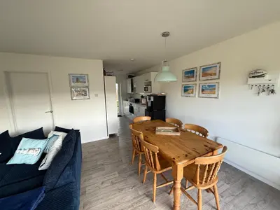 a living room with a wooden table and a blue couch at The White House in St Merryn