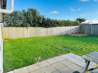 a backyard with a wooden fence and a green yard at The White House in St Merryn