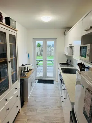 a kitchen with white cabinets and a door to a patio at The White House in St Merryn