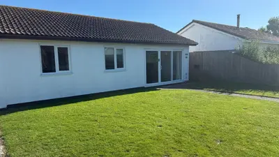 a small white house with a grass yard at The White House in St Merryn