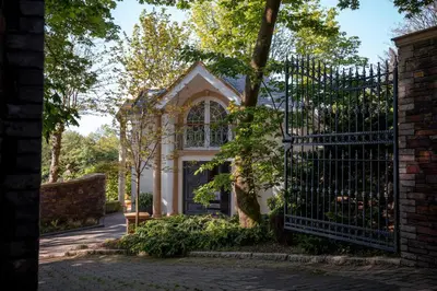 an iron gate to a house with a tree at Hunters Moon in St Austell