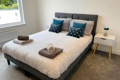 a bedroom with a bed with pillows and a cat on it at Coastal house, large garden, 4 bedrooms, 2 bathrooms, BBQ, 10 min walk to beach in Mawnan Smith