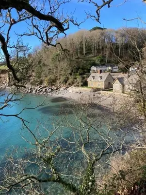 a house on the shore of a body of water at Coastal house, large garden, 4 bedrooms, 2 bathrooms, BBQ, 10 min walk to beach in Mawnan Smith