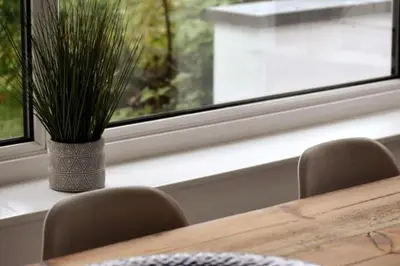 a vase of grass sitting on a table next to a window at Coastal house, large garden, 4 bedrooms, 2 bathrooms, BBQ, 10 min walk to beach in Mawnan Smith