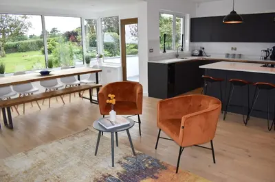 a kitchen and living room with chairs and a table at Coastal house, large garden, 4 bedrooms, 2 bathrooms, BBQ, 10 min walk to beach in Mawnan Smith