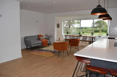 a kitchen and living room with a table and chairs at Coastal house, large garden, 4 bedrooms, 2 bathrooms, BBQ, 10 min walk to beach in Mawnan Smith