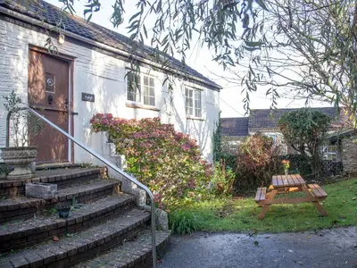 a house with stairs and a wooden bench in front of it at Hayloft - Uk48766 in Looe