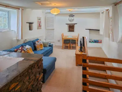 a living room with a blue couch and a table at Hayloft - Uk48766 in Looe