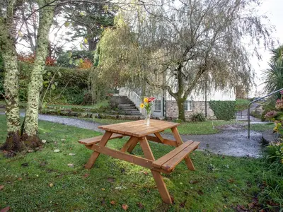 a wooden picnic table with a vase of flowers on it at Hayloft - Uk48766 in Looe