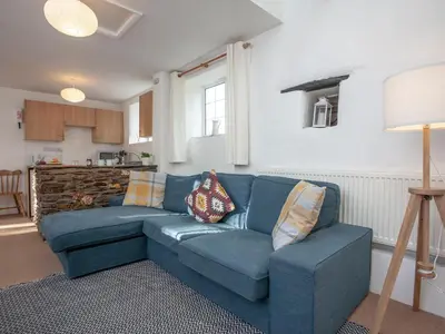 a living room with a blue couch and a kitchen at Hayloft - Uk48766 in Looe