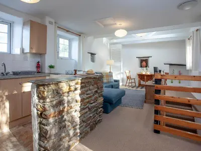a kitchen and a living room with a stone counter at Hayloft - Uk48766 in Looe